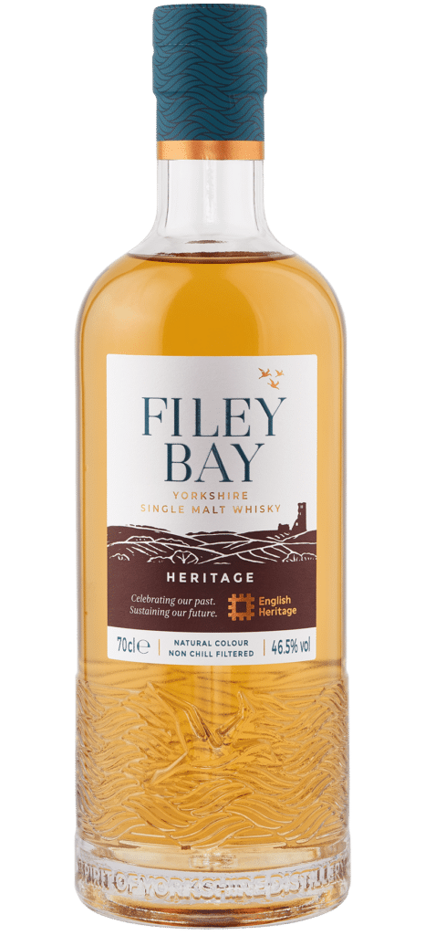 One hand holds a bottle of Filey Bay Heritage, with a glass in another
